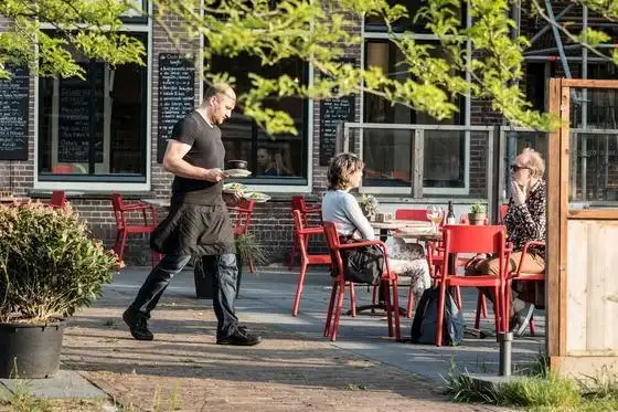 Medewerker met borden op terras De Oude Keuken